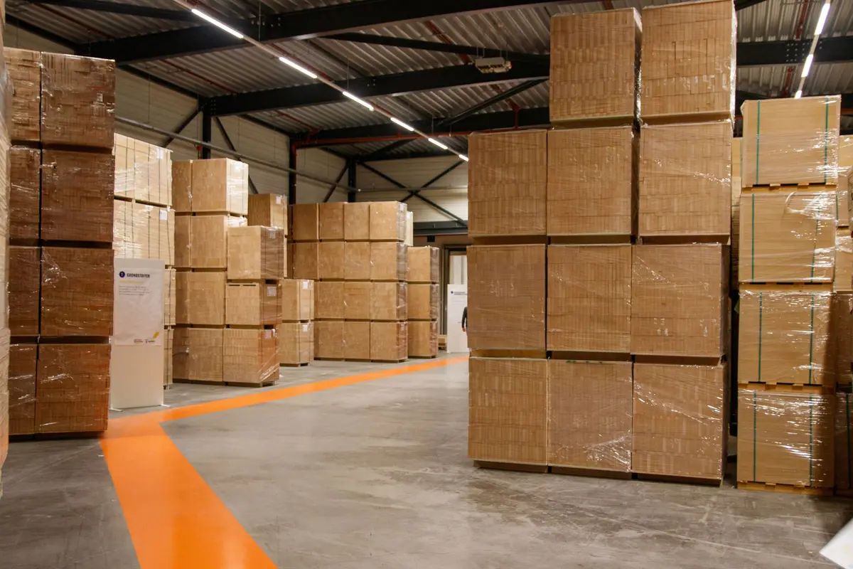 Pallets of boxed stock in a warehouse beside an orange floor marking